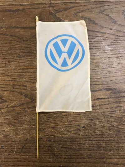 An original 1960's VW dealership desk flag. It is in very good used condition and has been in a private collections for over twenties years in a display cabinet. The flag has no hole or damage and the blue VW logo is clear, there are a couple of small stains (please view photos). The pole is a gold colored metal and in superb condition, the bottom is pointed and the other has a nice detailed top. This would have been more than likely in a VW dealership on a desk as a decorative item. It is a rare and collectible item!